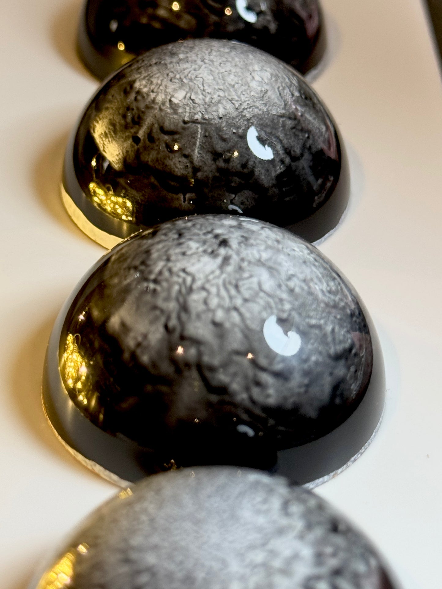 Close-up of shiny, black, reflective chocolates on a light background