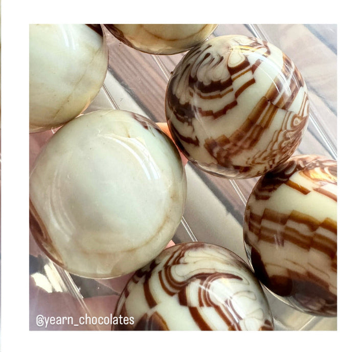 An image of yearn bonbons that show the organic nature of different types of chocolate poured into a mould at the same time. 