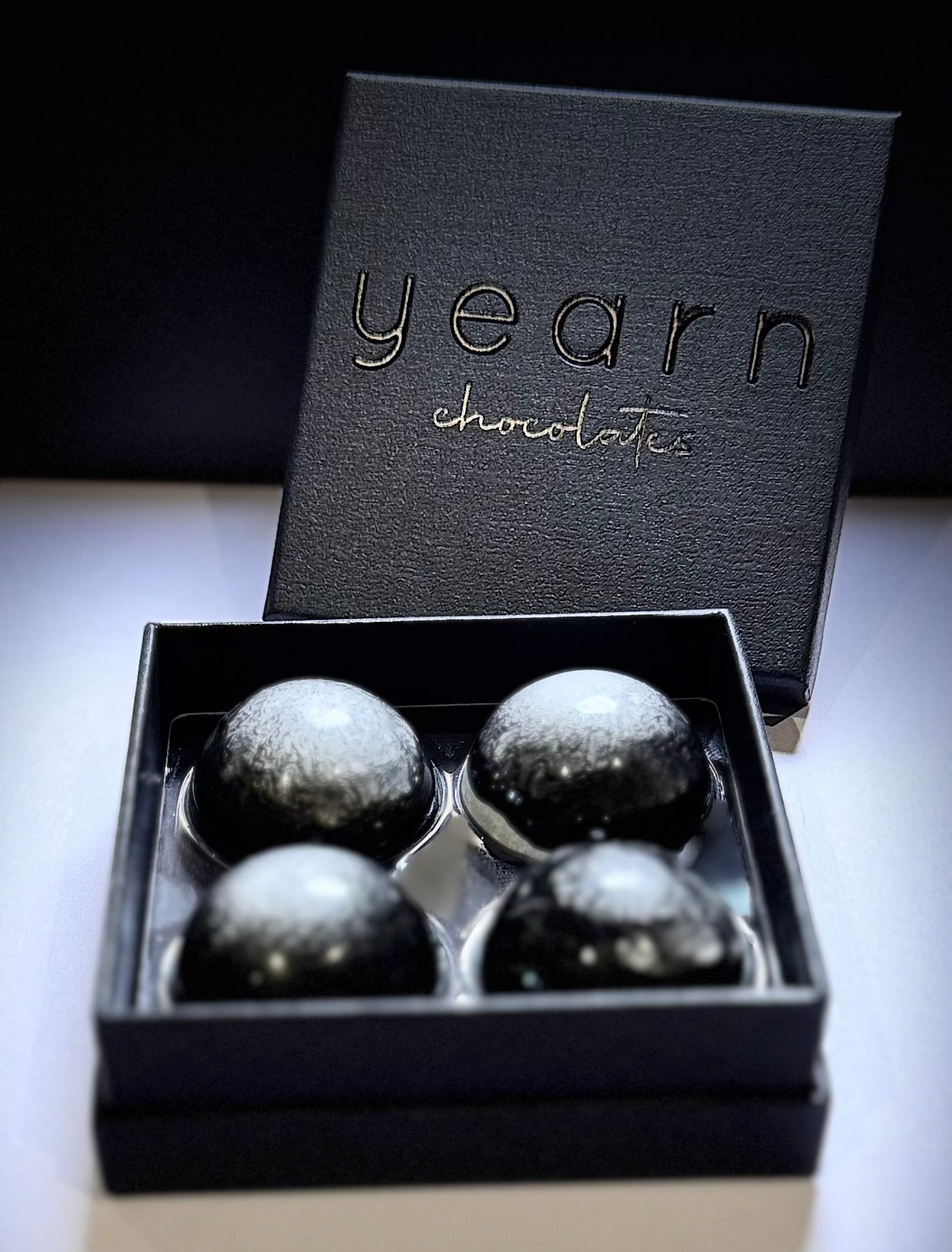 Box of chocolates with 'yearn chocolates' branding on a dark background